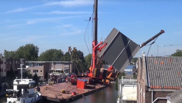 The first crane collapses onto houses after overbalancing.