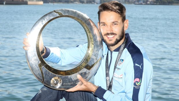 Milos Ninkovic, with the A-League Championship trophy at Mrs Macquaries Chair on Tuesday, has announced he has re-signed with Sydney FC as a marquee player.