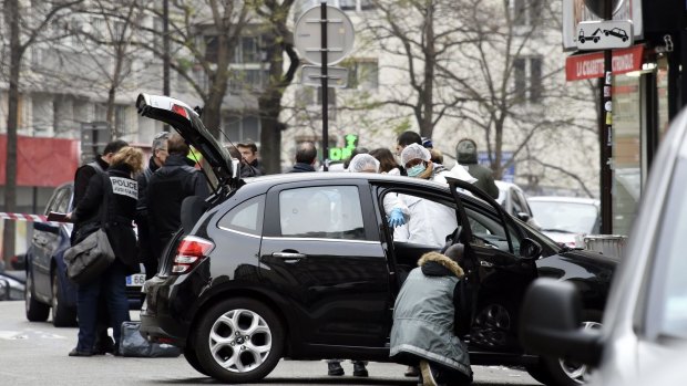 French police officers and forensic experts examine the car used by armed gunmen who stormed the Paris offices of satirical magazine <i>Charlie Hebdo</i>