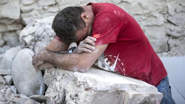 A man leans on rubble following an earthquake in Amatrice, Italy.