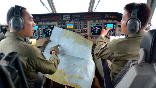 Pilot of navy airplane CN235 M. Naim holds a map to co-pilot Rahmad while flying over the Java sea during joint search operations for QZ8501.