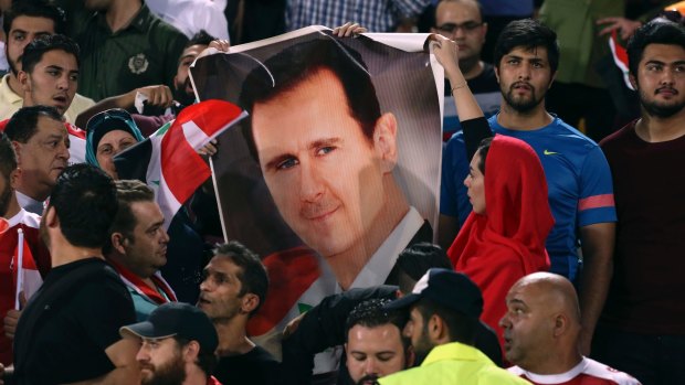 Political minefield: Syrian fans hold a portrait of President Bashar Assad, before their draw with Iran that qualified the team for the play-off.