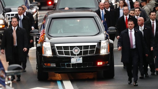 Members of President Donald Trump's Secret Service detail walk with the First Family's motorcade vehicle as they move along the Inauguration Day Parade Route in Washington.