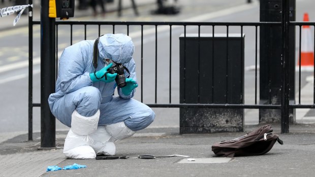A forensic officer takes photographs of knives on the ground near a backpack after Mr Ali's arrested on Parliament St, London.