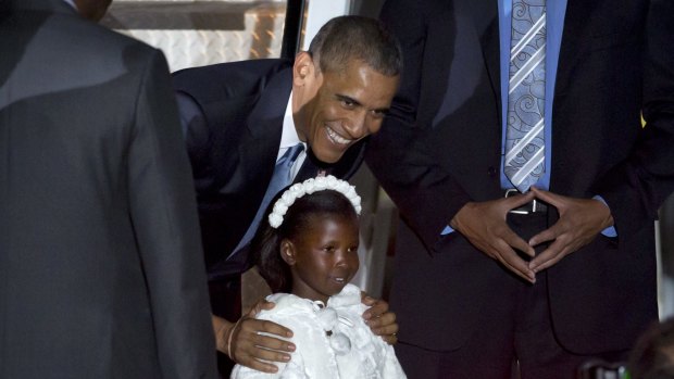 President Barack Obama poses for a photograph with Joan Wamaitha, 8, who gave him flowers on his arrival at the Jomo Kenyatta International Airport in Nairobi, Kenya.