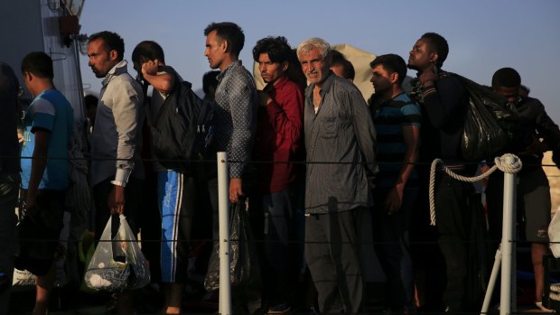 Migrants line up onboard an Italian coast guard vessel before disembarking at the port of Kos on Friday.