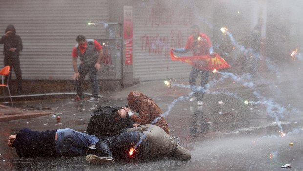 Demonstrators try to protect themselves from water, sprayed by a police water-cannon truck, and tear gas during clashes in Istanbul on Friday.