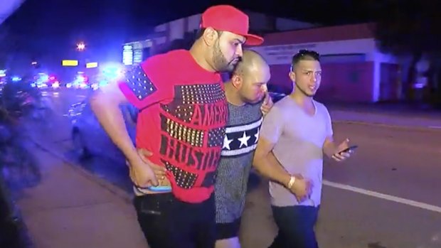 An injured man is escorted out of the Pulse nightclub in Orlando, Florida.