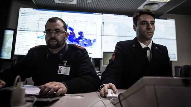 Italian coast guard officers use monitors to track ships navigating the area where the boat believed to be crowded with perhaps as many as 700 migrants capsized in the waters north of Libya.