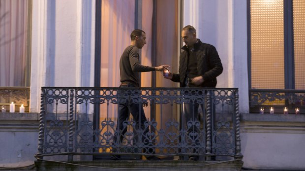 Mohammad Abdeslam, left, the brother of Paris attackers Salah and Brahim Abdelslam, lights candles with an unidentified man on the balcony of his house during a candlelight vigil in the town square of Molenbeek, Belgium, after the attacks. 
