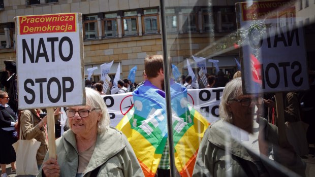 A woman holds a banner during an anti-NATO protest joined by hundreds in Warsaw, Poland, on Saturday.