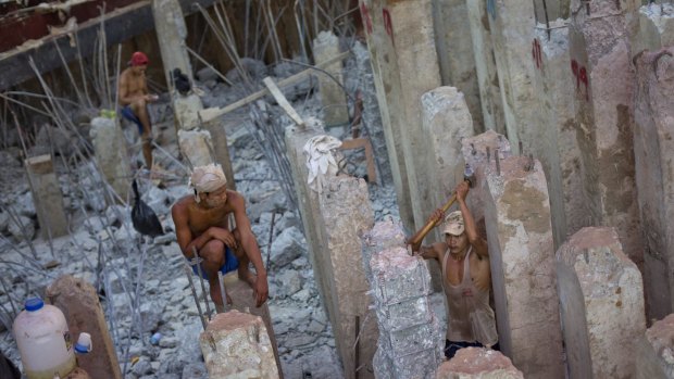 Myanmar construction workers partially demolish a foundation of a building under construction in Yangon on Tuesday. 