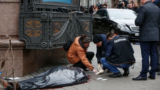 Forensic experts and police officers examine the scene following the killing of Denis Voronenkov in Kiev, Ukraine.