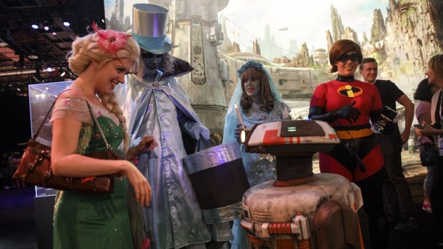 Attendees in costume interact with a droid in the Walt Disney Co. Star Wars: Galaxy's Edge exhibit at the D23 Expo 2017 .