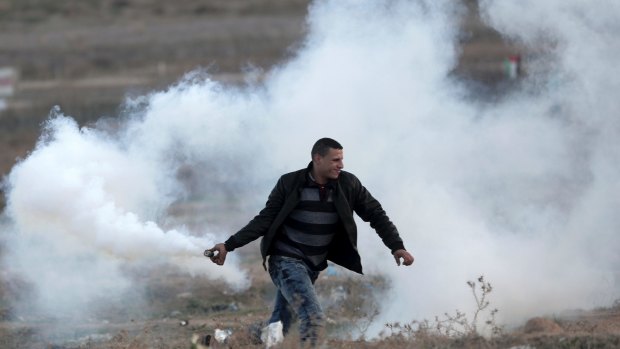 A Palestinian protester prepares to throw back a teargas canister that was fired by Israeli soldiers, during clashes on the Israeli border with Gaza.
