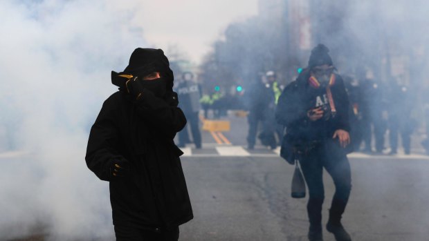 Anonymous no more?: A protester shields his mouth and nose from gas fired by police during a demonstration after the inauguration of US President Donald Trump.