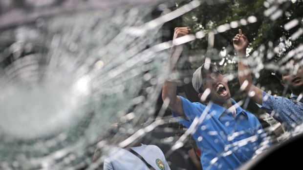 Taxi drivers are seen through the smashed windshield of a taxi during a protest against  ride-hailing apps  in Jakarta.