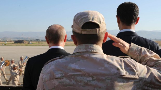 Russian President Vladimir Putin, left, and Syrian President Bashar al-Assad, right, watch troops marching at the Hemeimeem air base in Syria, on Monday.