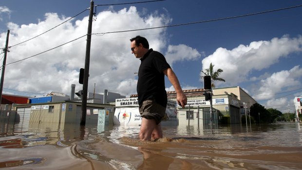 In January 2011, West End business owner Ross Clayton wades through knee-high water on Montague Road. A second class action for the flood event is under way.