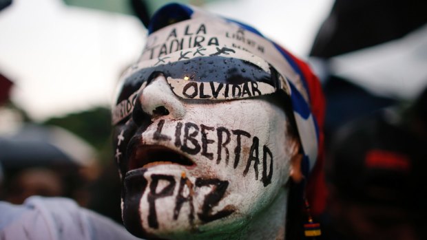 A woman with her face painted with Spanish words "Freedom, peace, don't forget" attends a vigil to honour the more than 90 people killed during three months of anti-government protests in Caracas, Venezuela.