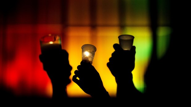 Mourners hold up candles against a rainbow-lit backdrop in Orlando during a vigil for the victims of the Pulse nightclub shooting.