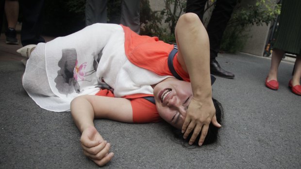 Fan Lili, wife of imprisoned activist Gou Hongguo, on the ground after an interaction with a police officer outside the Tianjin court.