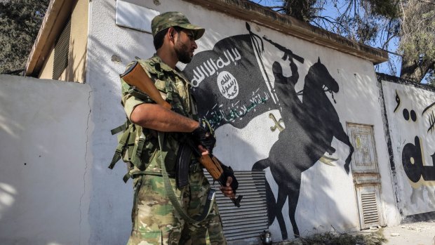 A Free Syrian Army fighter stands in front of a painting left by IS militants in Jarablus, Syria.