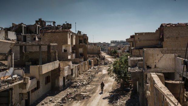 A Syrian Democratic Forces fighter walks through the destroyed streets of Raqqa.