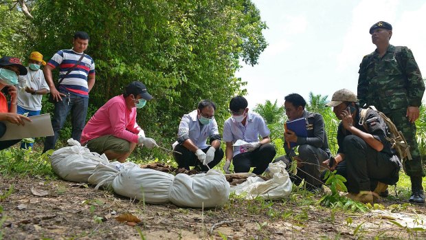Doctors inspect human remains in the Thai jungle near the border with Malaysia.