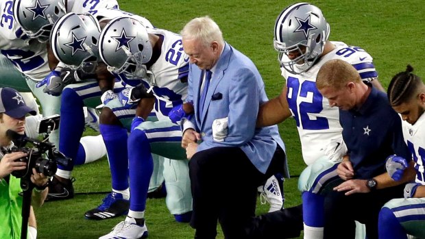 Dallas Cowboys, led by owner Jerry Jones, center, take a knee prior to the national anthem.