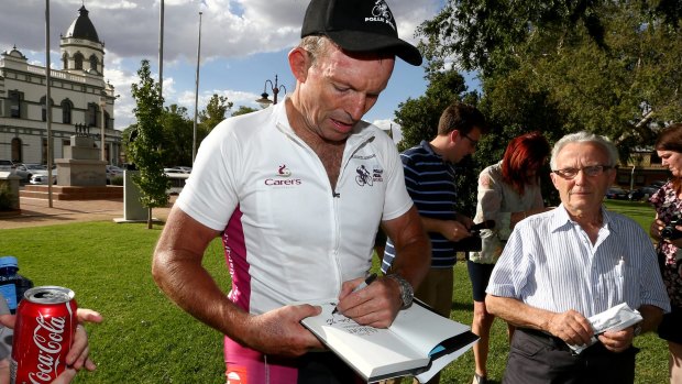 Mr Abbott signs a copy of his book.