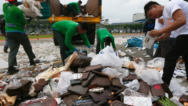 Workers cut fake handbags in a symbolic destruction of counterfeit goods in the Philippines in July this year.