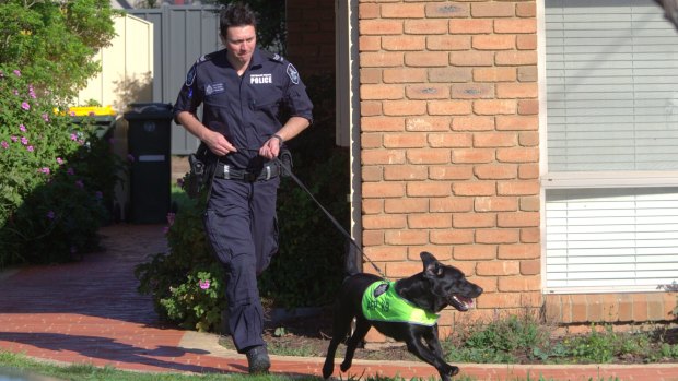 A police officer runs around the Seabrook house raided on Tuesday morning. 