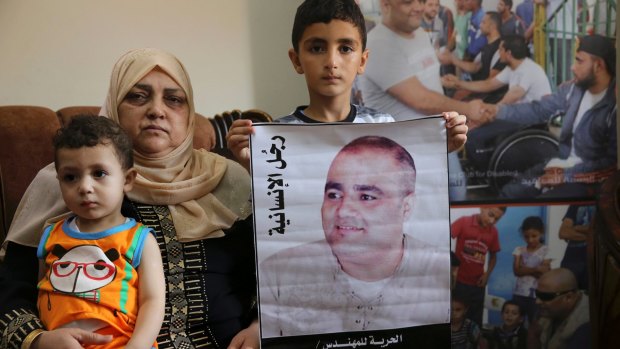 Amal el-Halabi holds her grandson Fares, 18 months old, while her grandson Amro, 7, holds a picture of his father Mohammed el-Halabi, World Vision's Gaza operations manager, who Israel accuses of diverting funds to Hamas. The alleged figures exceed the total World Vision budget for Gaza.