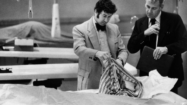 San Francisco homicide inspectors David Toschi, left, and William Armstrong go through a murder victim's clothes at the morgue in the Hall of Justice in San Francisco in 1974. 