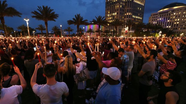 Thousands hold candles in the air after a bell tolled for each of the victims during a vigil on Monday.