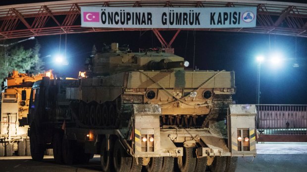 Turkish military trucks carrying tanks and other armoured vehicles cross through a border gate into a Turkish-controlled region of the Oncupinar border crossing with Syria. The deployment occurred hours after dozens of Turkish jets bombed Syrian Kurdish militia targets in the enclave of Afrin. 