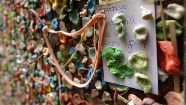 A note that reads "Goodbye Gum Wall, we will miss you," sticks to a wall partially obscured by gum.