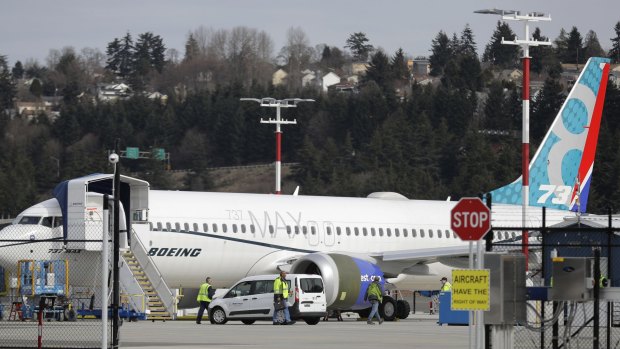 Workers walk next to a Boeing 737 MAX 8 airplane parked at Boeing Field in Seattle. 