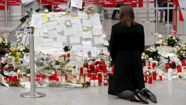 Investigation into tragedy continues: A woman kneels in front of candles and flowers as she prays for the victims of Germanwings Flight crash.