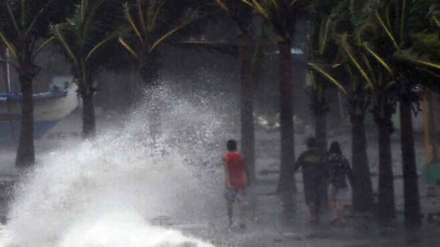Residents walk past high waves brought about by strong winds as it pound the seawall, hours before Typhoon Hagupit passes near the city of Legazpi. 