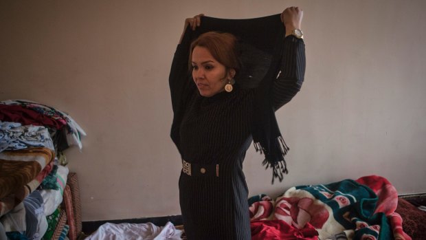 Zahra Yaganah, an activist, writer and mother of two teenagers, puts on her headscarf before she goes to work in Kabul.