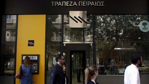 A customer uses an ATM outside a branch of Piraeus Bank in Athens.