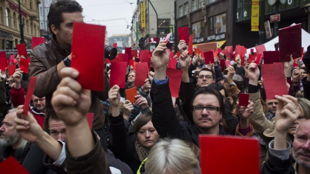 People in Prague show red cards as they protest against President of Czech Republic Milos Zeman near a memorial to students who were attacked by riot police in 1989.