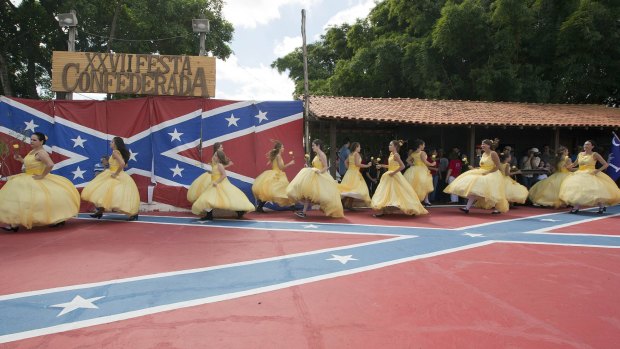 Teenage girls pulled hoop skirts over their cut-off short-shorts and wiggled into bustier tops, taking to the stage painted with a giant Confederate flag on the arms of young men in grey and yellow uniforms.
