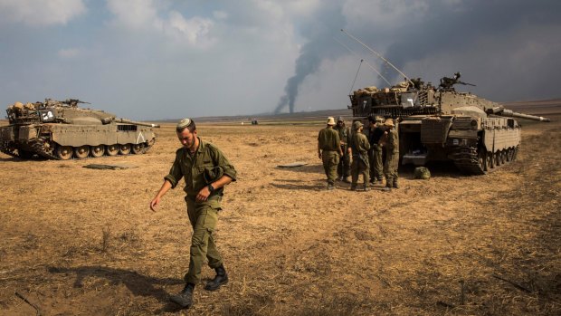 New threat: Israeli soldiers stand near their tank while smoke from air strikes and shelling rises from Gaza on July 22 near Sderot, Israel. 