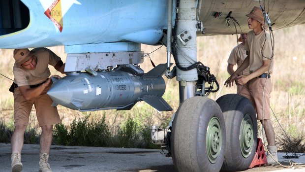 Russian military support crew attach a satellite-guided bomb to a jet fighter in Syria.