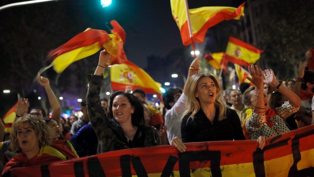 Anti-independence supporters shout slogans and wave Spanish flags as they march against the unilateral declaration of independence approved earlier by the Catalan parliament in Barcelona.