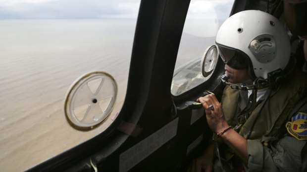 A crew member of an Indonesian Air Force Super Puma helicopter looks out a window  during a search operation for the crashed AirAsia Flight 8501 over the Java Sea.