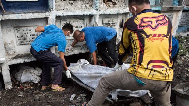 Morgue workers carry an unclaimed body and victim of an extrajudicial killing in Manila, Philippines last week.